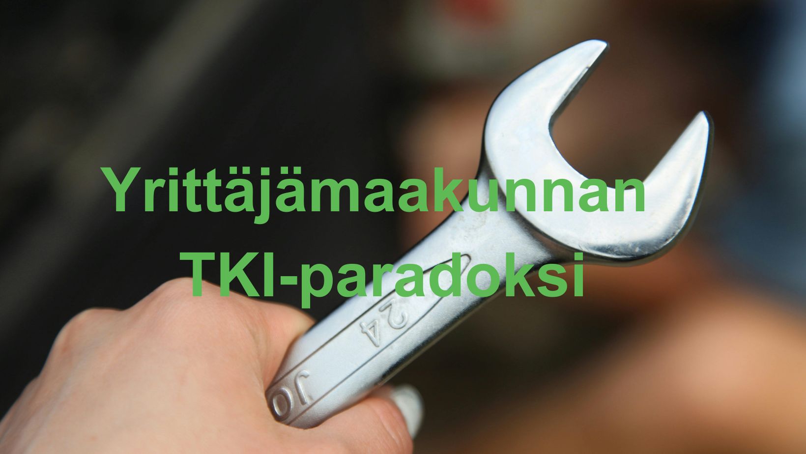 Teksti: Yrittäjämaakunnan TKI-paradoksi. Kuvassa käsi ja kiintoavain.